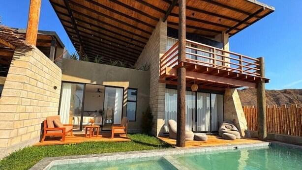 Una casa moderna con piscina, balcón y mobiliario de exterior.