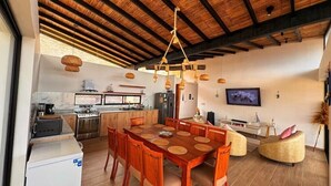 Una cocina moderna con armarios de madera, un comedor con una mesa grande y sillas de madera, y una sala de estar con un sofá y una televisión.