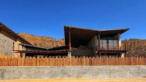 Un edificio moderno con fachada de madera, un balcón y vistas a un paisaje montañoso.