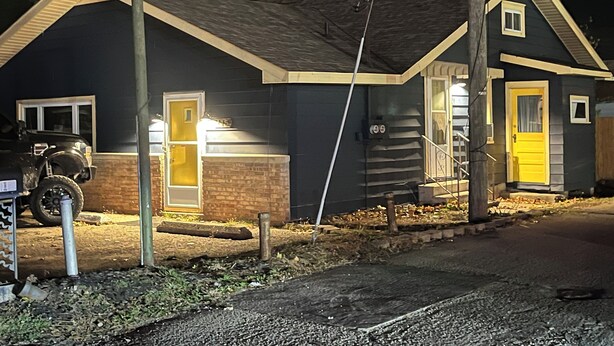 Kaksikerroksinen talo, jossa on autotalli, sen sivussa näkyy numero '905' ja talossa on keltainen ovi.
