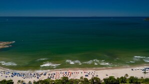 A beach with clear waters, a sandy shore, and numerous beach umbrellas. - Casa Premium com Piscina e rea Gourmet - Camburi (São Sebastião)