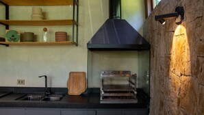 A kitchen with a built-in oven, a sink, and a wooden cutting board. - Casa Premium com Piscina e rea Gourmet - Camburi (São Sebastião)