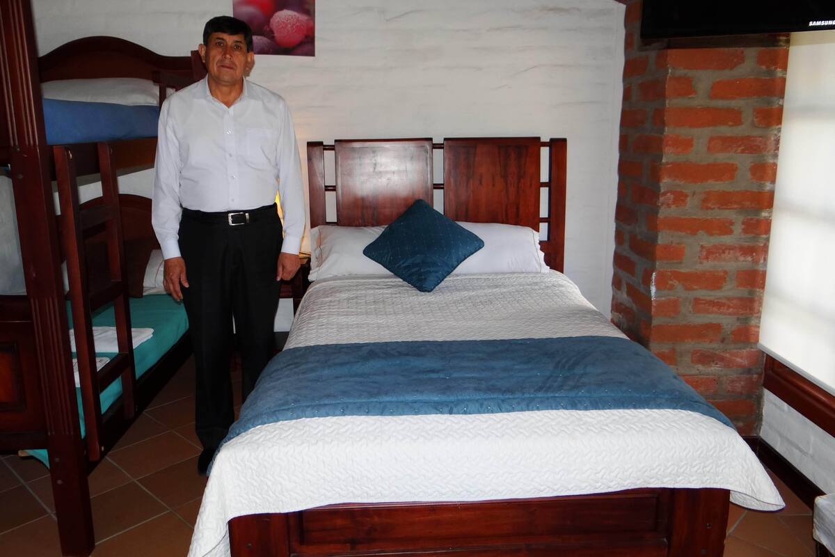Ein Hotelzimmer mit einem hölzernen Bett, einem Etagenbett, einer Backsteinwand und einem an der Wand montierten Fernseher.