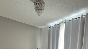 Une chambre à coucher moderne avec un grand lit, une table de chevet, une chaise et un vase décoratif.