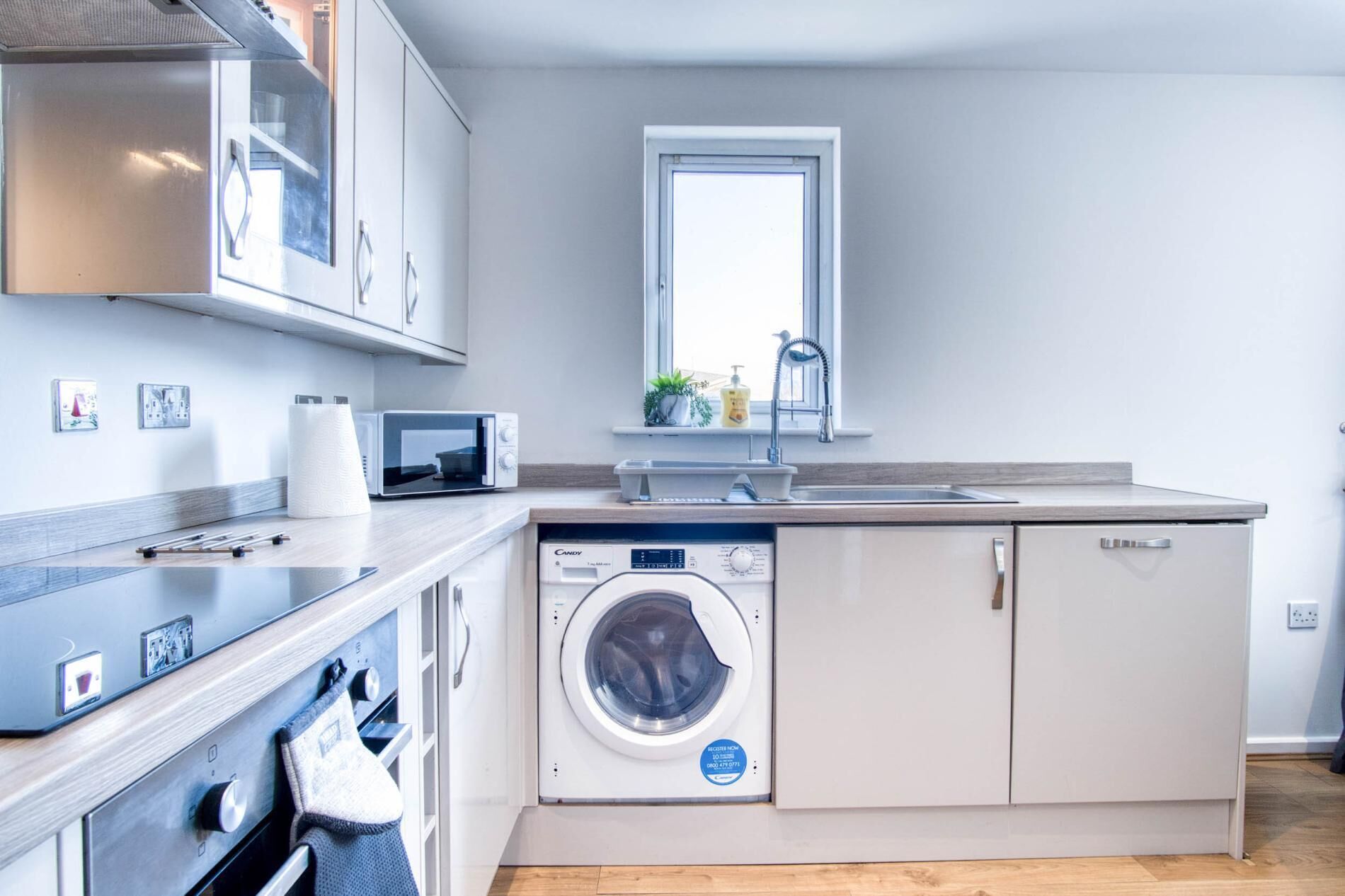 Une cuisine compacte équipée d’un lave-linge, d’un four à micro-ondes et d’un évier.