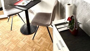A modern room with a flat-screen TV mounted on the wall, a small table with a chair, and a cabinet with a remote control. - Studio im Zentrum, Schwimmbad und 400m von Skiliften entfernt by Interhome (St. Moritz)