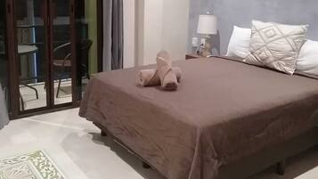 A bedroom with a bed, a nightstand, a wall-mounted macrame piece, and a sliding glass door leading to an outdoor area.