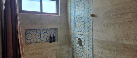 Un baño con cabina de ducha de vidrio, una ventana sobre la ducha y un perchero para toallas.