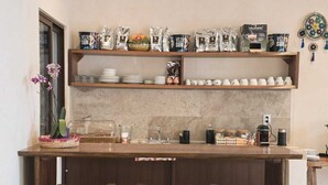 A kitchen with wooden bar stools, a coffee machine, and various kitchenware on shelves. - Casa Lucia B&B Valladolid  (Valladolid)