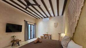 A bedroom with a large bed, a flat-screen TV mounted on the wall, a desk with a chair, and a ceiling fan. - Casa Lucia B&B Valladolid  (Valladolid)