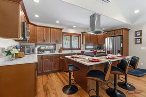 A modern kitchen with wooden cabinets, a stainless steel refrigerator, and a central island with bar stools. - New Build, Single level, A/C, Fireplace, Covered Deck (Durango)