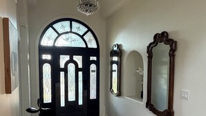A hallway with a wooden bench, a chandelier, a large mirror, and a stained glass door. - Spacious 5-bedroom  3.5 bath home on 1/2 an acre in Mission.  Pet friendly. (Mission)
