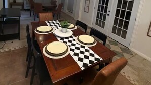 A dining area with a wooden table, chairs, and a ceiling light fixture. - Spacious 5-bedroom  3.5 bath home on 1/2 an acre in Mission.  Pet friendly. (Mission)
