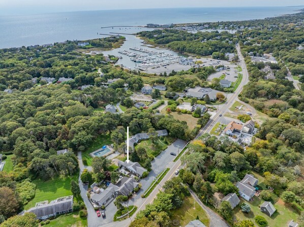 Vue aérienne d’une zone résidentielle côtière, avec des maisons, un port de plaisance et un phare.