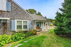 Une maison de plain-pied dotée d’un porche abrité, d’un petit jardin agrémenté de pas japonais et d’une pelouse bien entretenue.