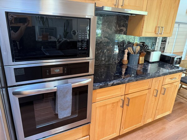 A kitchen with stainless steel appliances, wooden cabinets, and a countertop with various utensils. - Aptos Hills Getaway - Welcome to Oak Landing (Aptos)