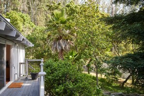 Une maison avec un porche, un palmier et de la verdure tout autour.
