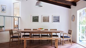 A dining area with a wooden table, benches, and chairs, a hanging light fixture, and framed artwork on the wall. - Aptos Hills Getaway - Welcome to Oak Landing (Aptos)