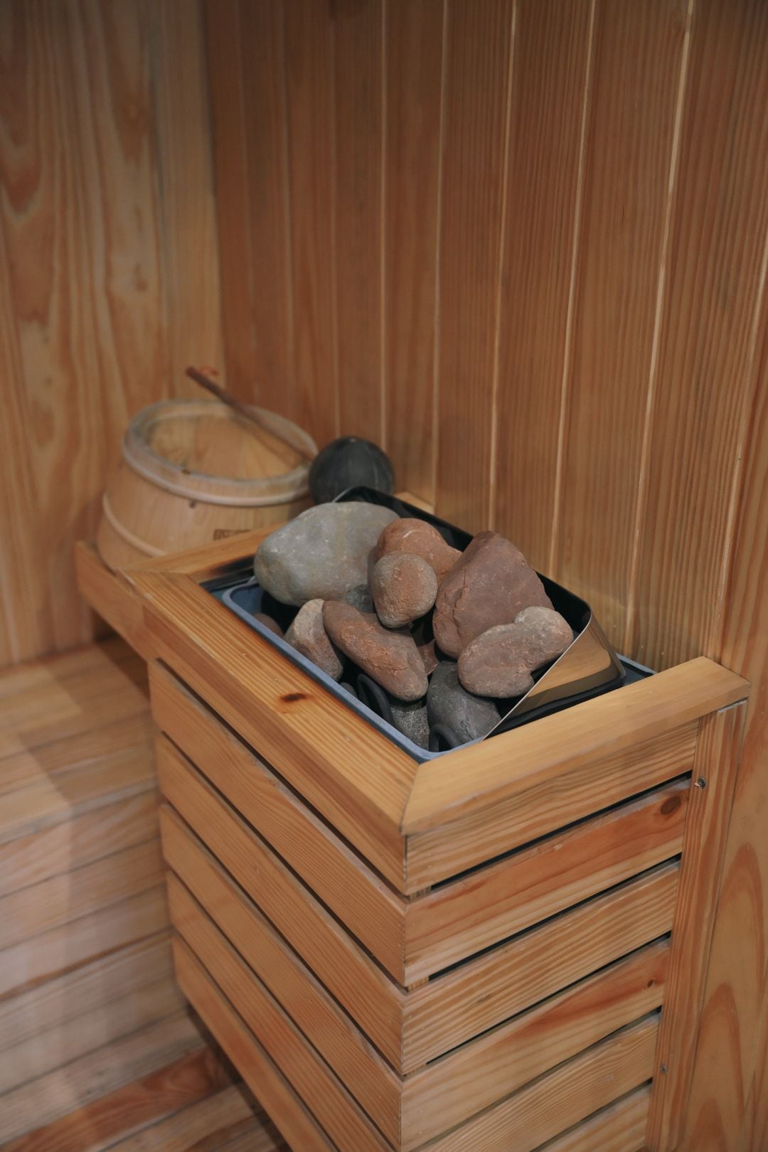 Una sauna con paredes de madera y una pileta de piedra llena de piedras calientes.