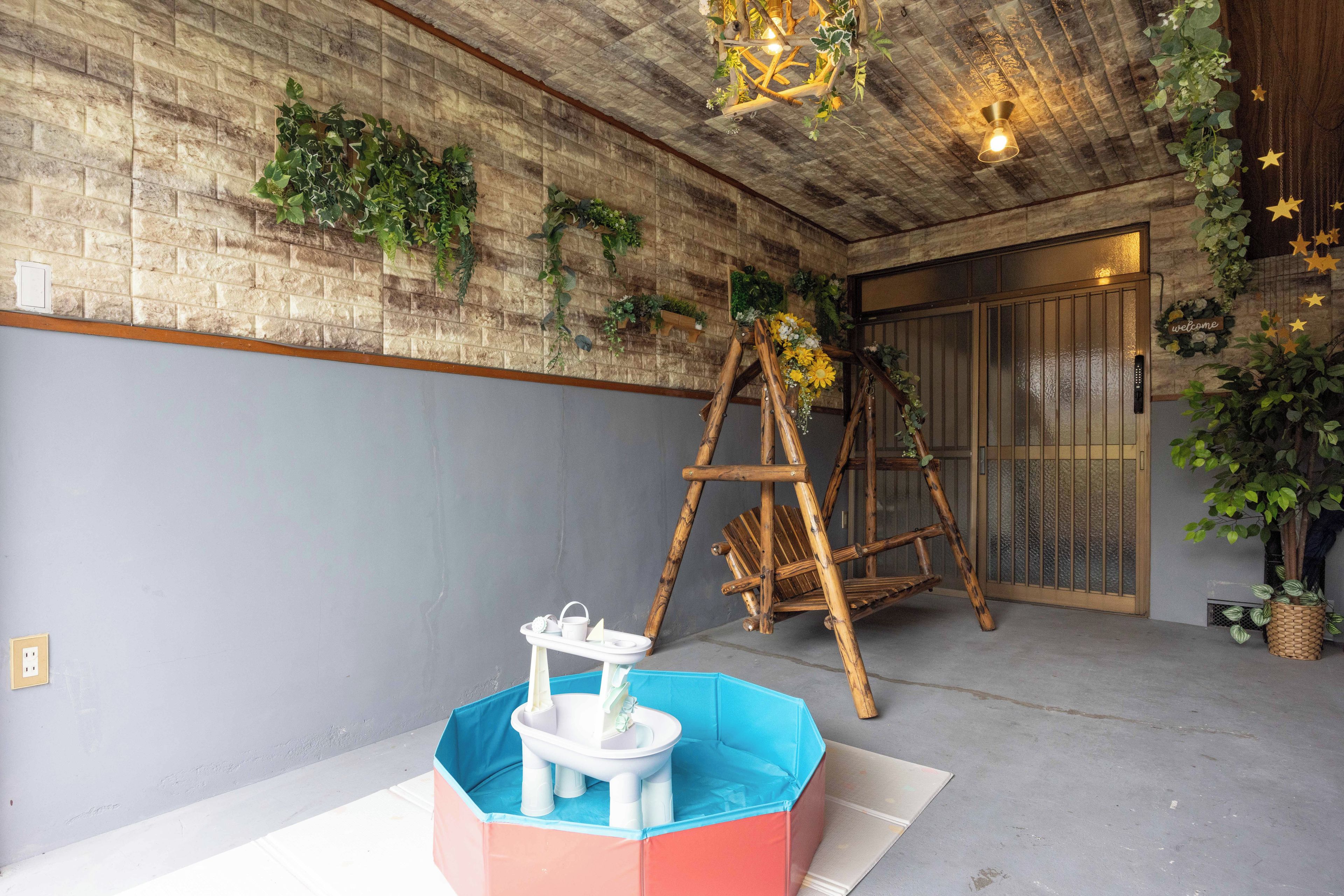 A room with a brick wall, a wooden ladder, and a blue and pink play structure.