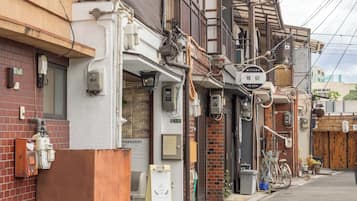 A narrow urban street with traditional Japanese buildings, a bicycle, and a small shop.