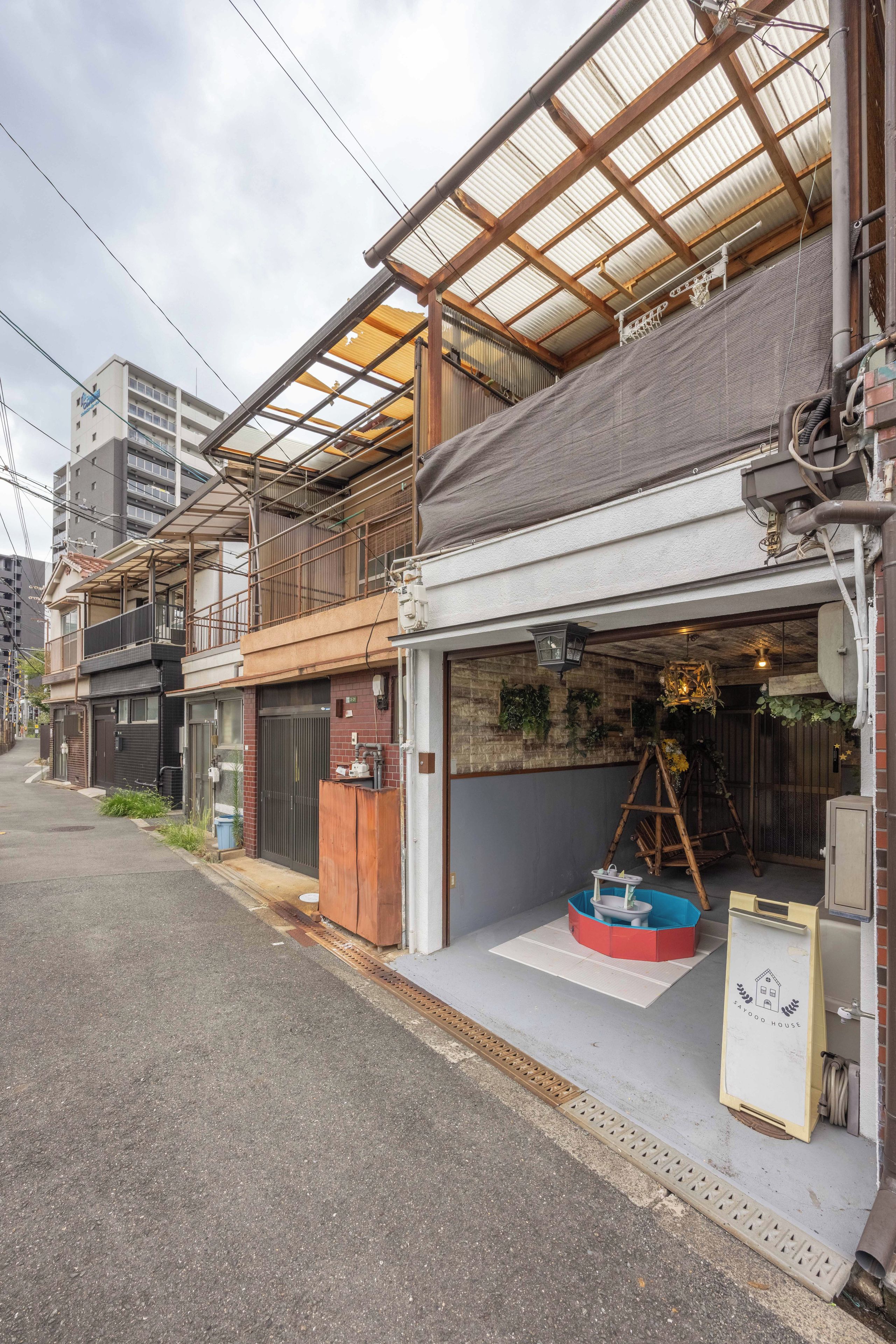 A traditional Japanese building with a covered entrance, a wooden ladder, and a signboard outside.
