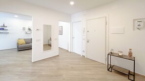 Een modern interieur met een houten vloer, een bank met een geel kussen, een spiegel en een tafel met decoratieve objecten.
