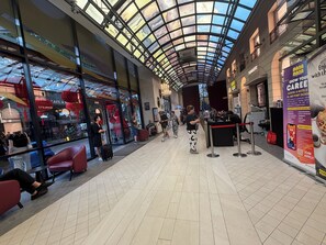 Un vaste espace intérieur doté d’un haut plafond et de grandes fenêtres, comprenant des coins salon et un comptoir d’accueil.
