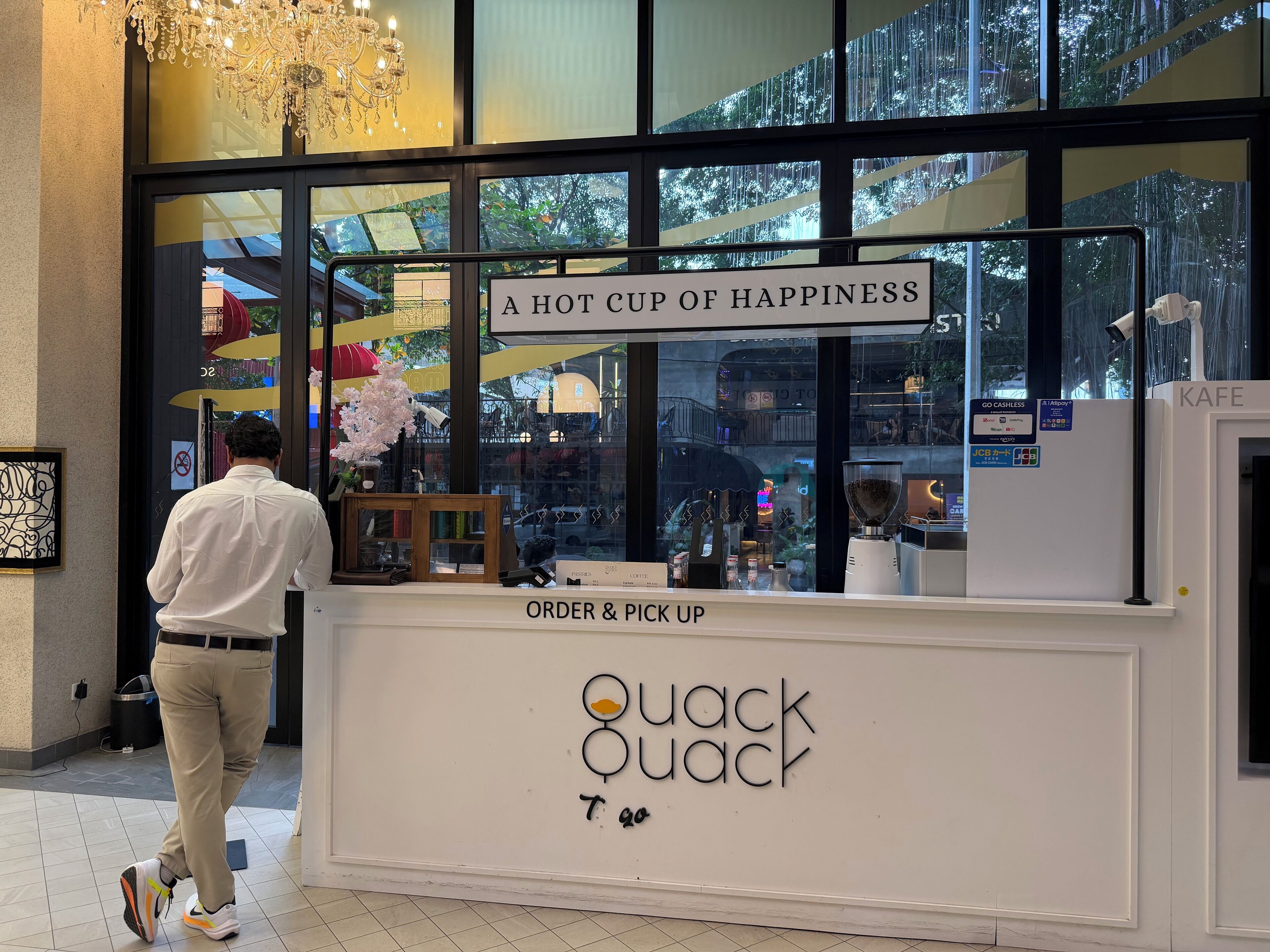 A coffee shop named 'Quack Quack' with a sign reading 'A HOT CUP OF HAPPINESS'.