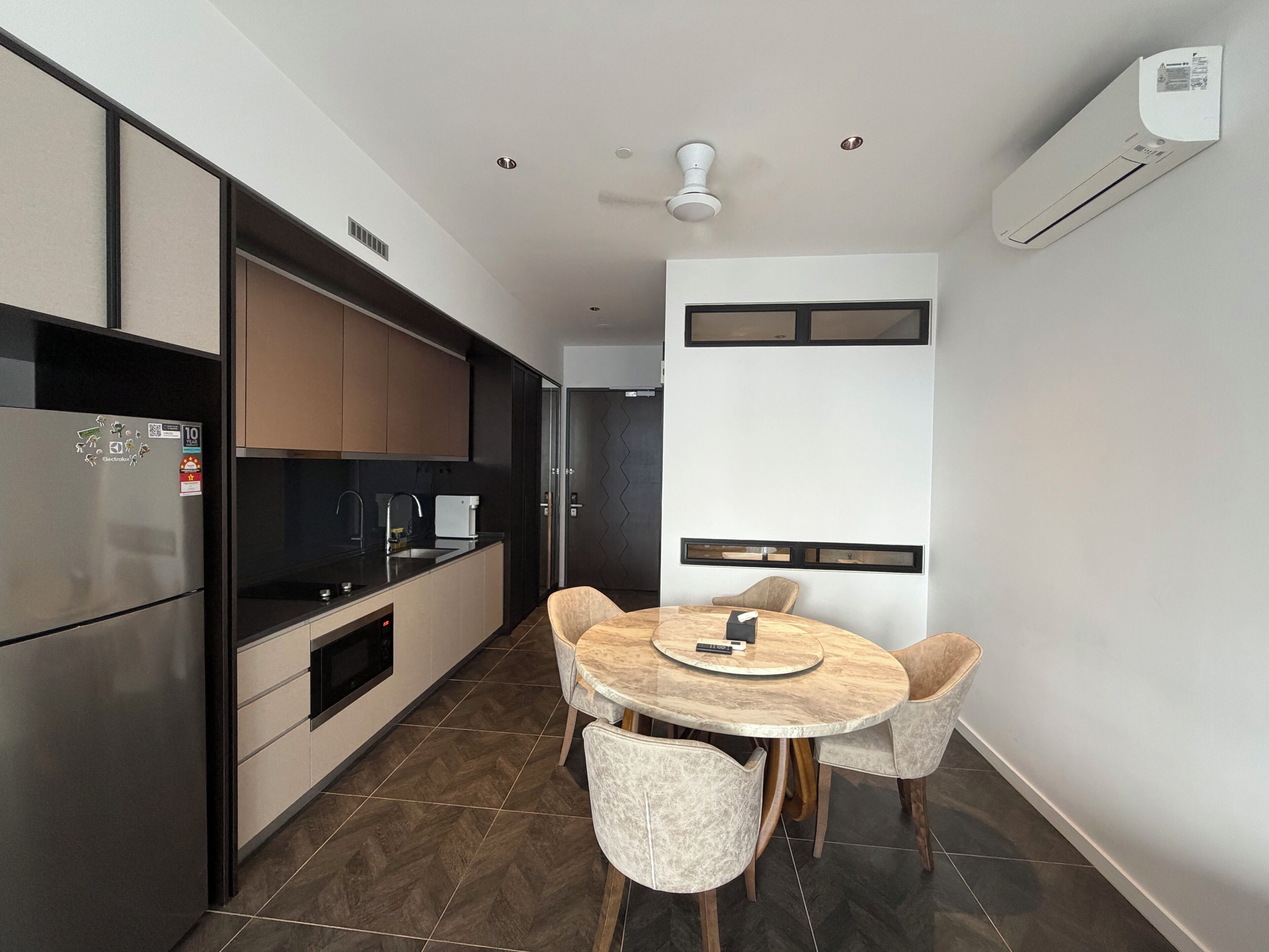 A modern kitchen with a built-in refrigerator, a coffee machine, and a dining area with a round table and four chairs.