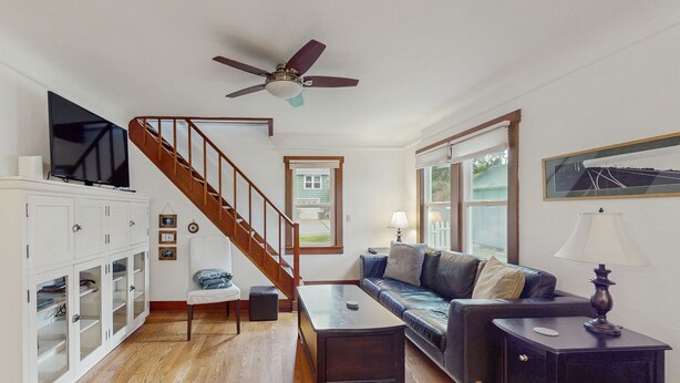 Ein Wohnzimmer mit Treppe, Fernseher, Sofa, Couchtisch und Schrank.