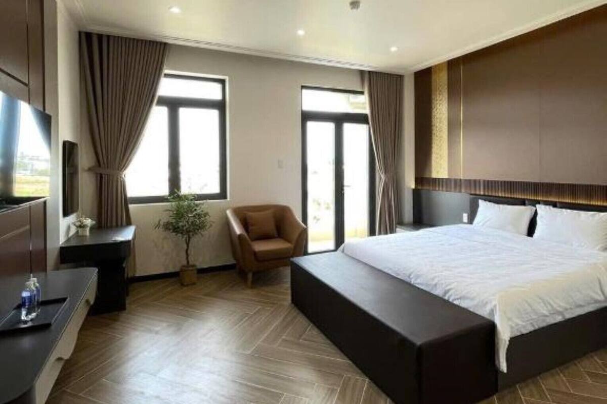 A modern hotel room with a large bed, a desk, a chair, and a TV.