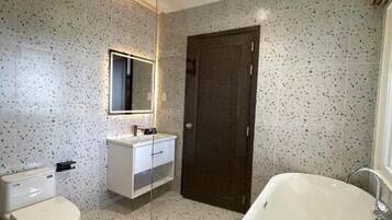 A modern bathroom with a freestanding bathtub, a toilet, and a vanity with a mirror.