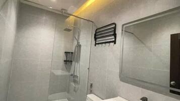 A modern bathroom with a glass shower enclosure, a white toilet, and a vanity with a mirror.