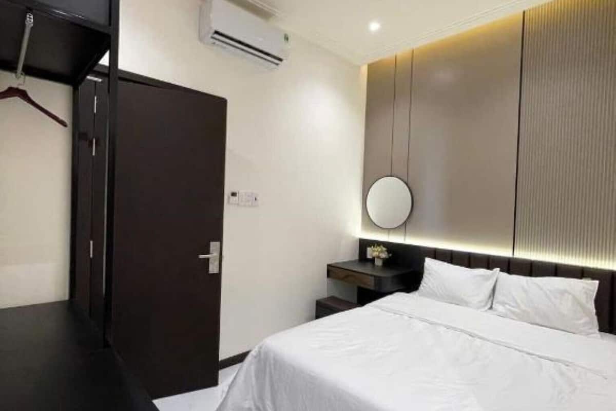 A modern hotel room with a bed, bedside table, and a mirror.