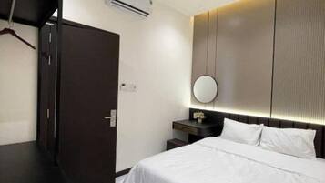 A modern hotel room with a bed, bedside table, and a mirror.