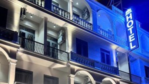 Un hotel con una entrada imponente, varios balcones y un letrero destacado.