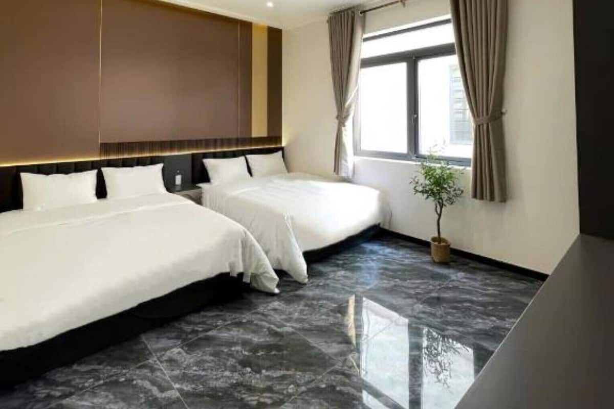 A hotel room with two beds, a large window with curtains, a potted plant, and a modern design.