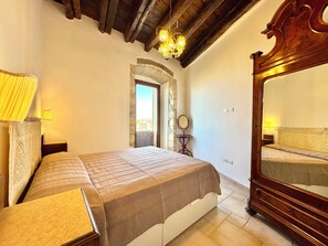 Une chambre à coucher avec un lit, un grand miroir, un lustre et une arche en pierre.