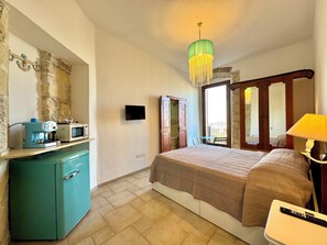 Ein Schlafzimmer mit einem Bett, einem Schreibtisch mit Mikrowelle, einem Fernseher und einem grünen Schrank.