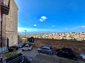 Blick auf eine Stadtansicht von einem Balkon mit Blick auf parkende Autos und eine Steinmauer.
