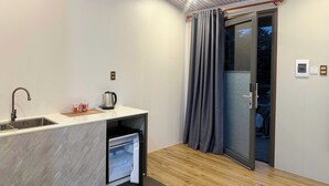 Una cocina compacta con un lavamanos integrado, una tetera y un refrigerador pequeño.