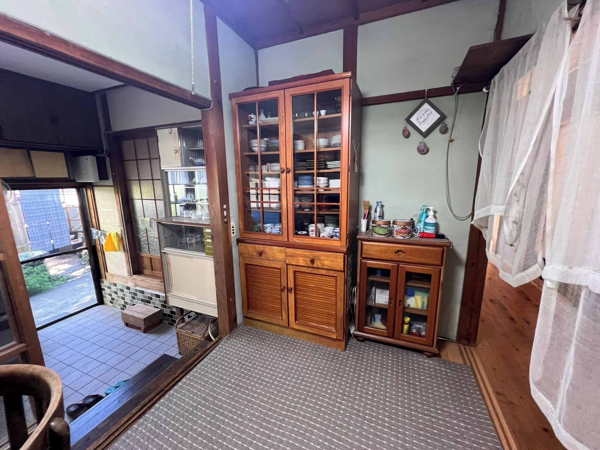 A traditional Japanese room with tatami flooring, a wooden cabinet with glass doors, and a small table with a yellow cloth.