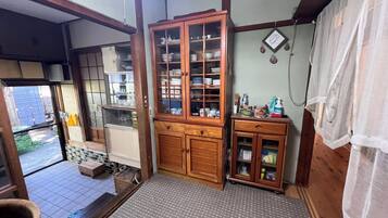 A traditional Japanese room with tatami flooring, a wooden cabinet with glass doors, and a small table with a yellow cloth.