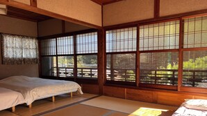 Et traditionelt japansk rum med tatamimåtter, en futon seng, shoji skærme og udsigt til en have.