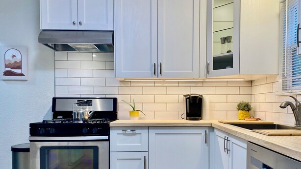 A modern kitchen with white cabinets, stainless steel appliances, and a small countertop area. - Location! Charming neighborhood Newly renovated Modern furnishings  Fab Staycay (Fort Worth)