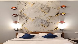 Un lit bien fait, avec un mur à motifs de marbre derrière, deux lampes de chevet et une tête de lit en bois.