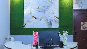 Un comptoir d'accueil, avec un mur à motifs de marbre derrière, un ventilateur de plafond et un panneau mural vert.
