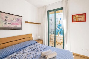Ein Schlafzimmer mit einem Bett, einem Nachttisch, einem Fenster mit Blick auf Gebäude und Kunstwerken an den Wänden.