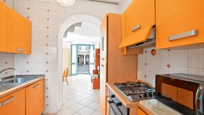 A kitchen with orange cabinets, a gas stove, and a tiled backsplash. - SeaEscape San Foca - Duplex with Sea-View Balcony, Melendugno, Italy (Melendugno)